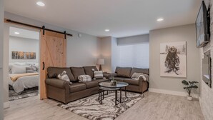 A modern living room with a sectional sofa, a glass coffee table, and a large painting on the wall.
