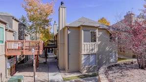 A small, single-story building with a chimney, a porch, and a small deck.