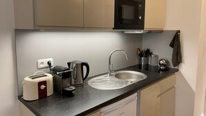 Una cocina compacta equipada con microondas, tostadora, hervidor y lavaplatos.
