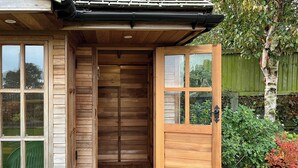 A wooden front door with glass panels, a wooden porch, and a brick step leading to the entrance. - 3 bedroom accommodation in Ashbourne (Ashbourne)