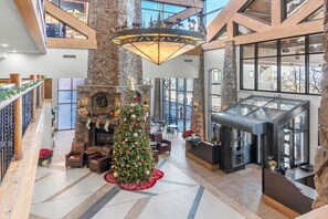 Un amplio vestíbulo con un gran árbol de Navidad, chimenea y una moderna recepción.