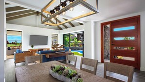 A modern living room with a dining area, a stone wall, and a large wooden door with a view.