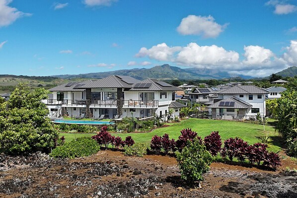 Un barrio residencial con varias casas, una piscina y montañas al fondo.