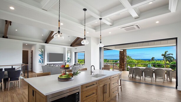 Una cocina moderna con una isla grande, armarios de madera e iluminación colgante.