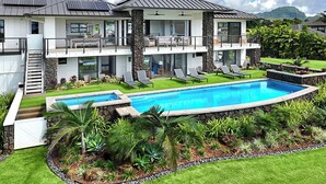 Una casa de dos pisos con piscina, balcón y vistas a las montañas.