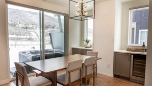 Eine moderne Küche mit einem großen Fenster, einem Essbereich mit Holztisch und -stühlen sowie einem eingebauten Backofen.