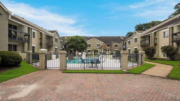 Un complejo residencial cercado con piscina, paseos pavimentados y jardines bien cuidados.
