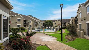 A residential building with a swimming pool, a lamp post, and a well-maintained garden.