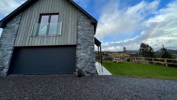 A modern building with a garage, stone facade, and a grassy area with a picnic table.