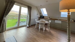 A spacious kitchen with a dining area, large windows, and a view of the countryside.