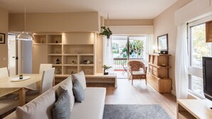A modern living room with a sofa, dining table, and built-in shelving.