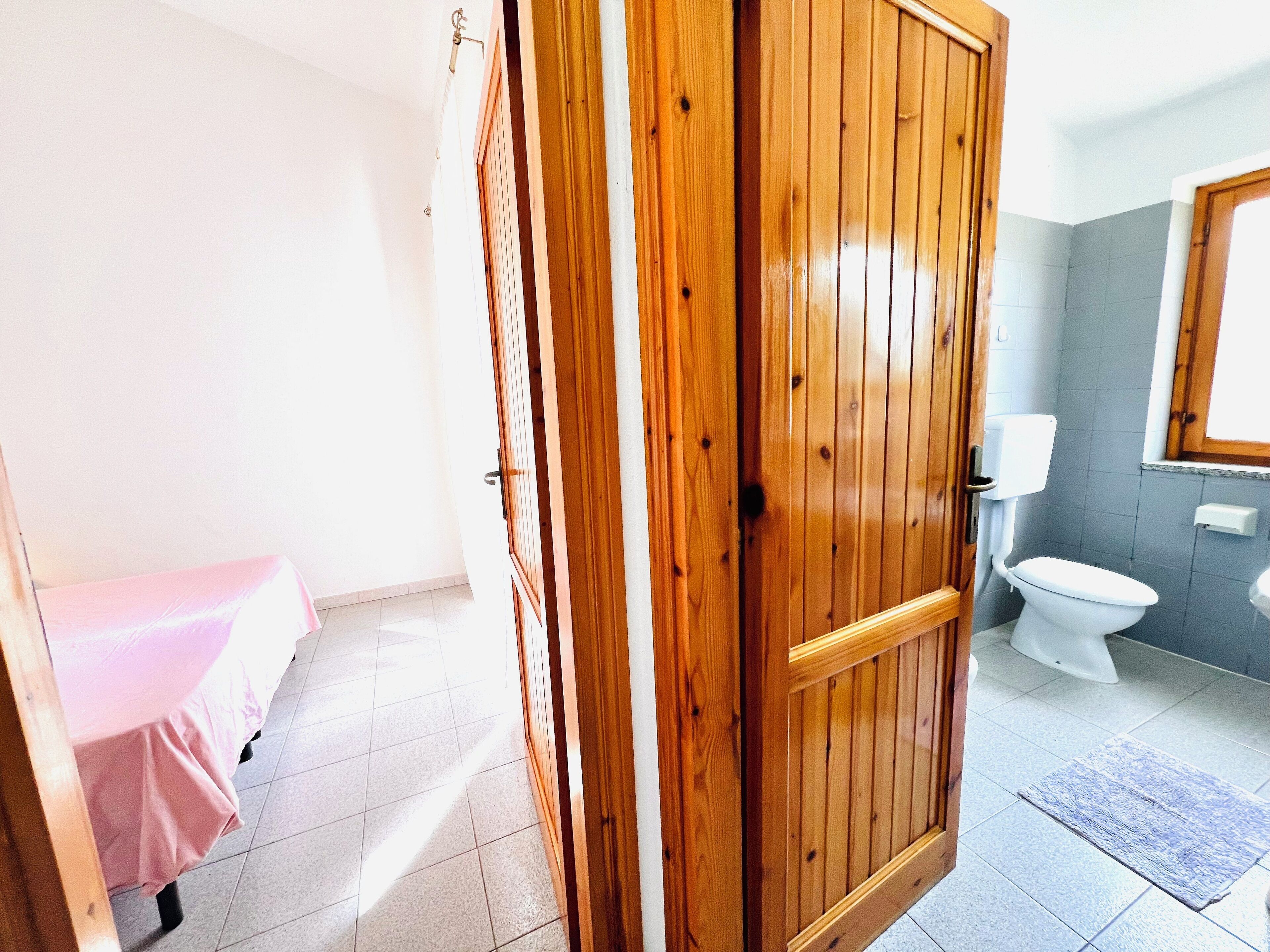 Un bagno con il water, un lavandino e una porta in legno.