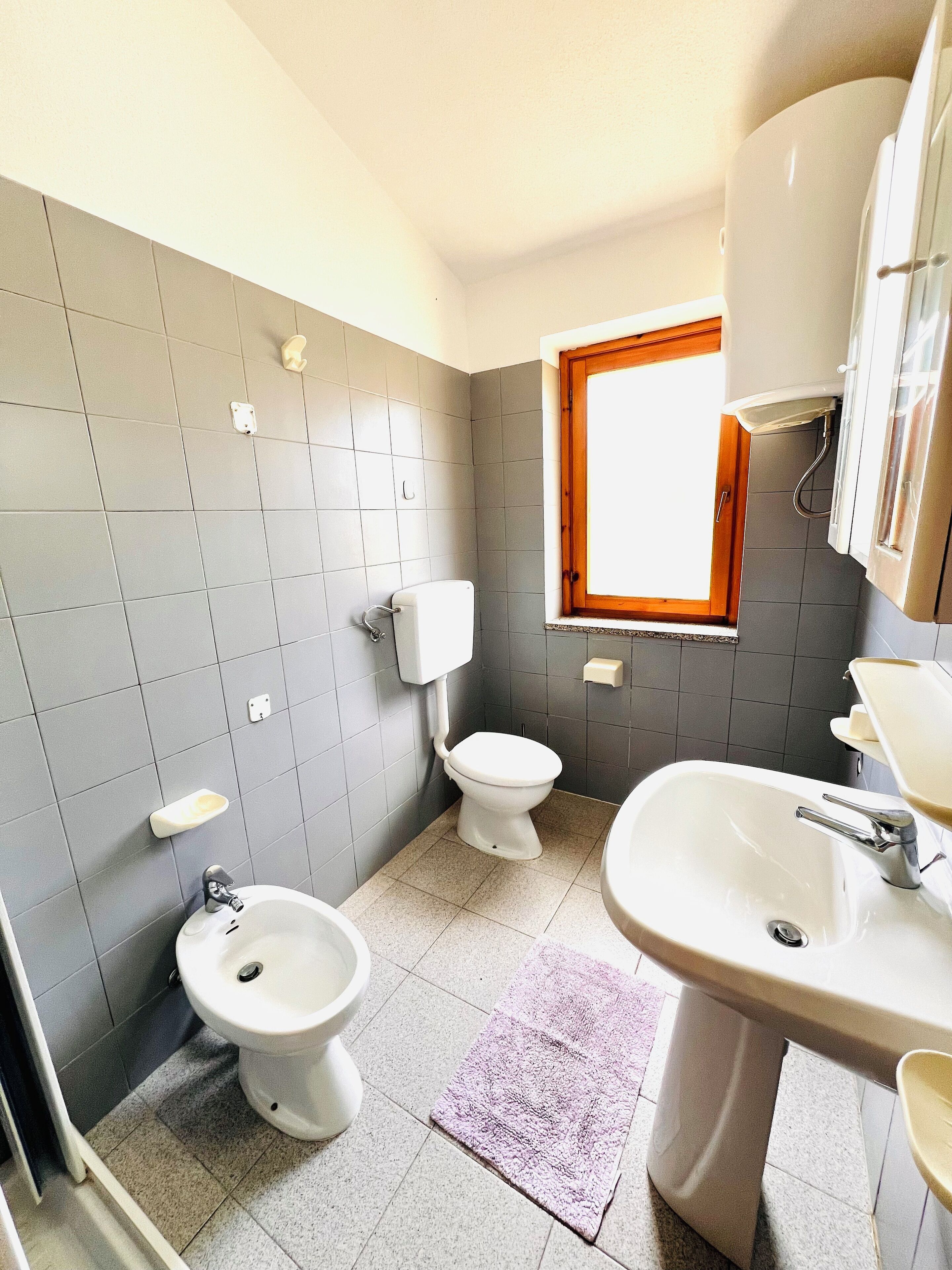 Une salle de bain comprenant des toilettes, un bidet, un lavabo et une fenêtre.