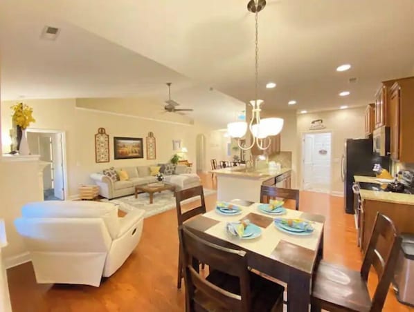 A spacious living area with a sofa, dining table, and kitchen in the background.