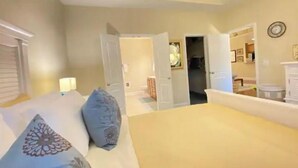 Ein Schlafzimmer mit einem Bett, Kissen, einem Nachttisch und einer Kommode.