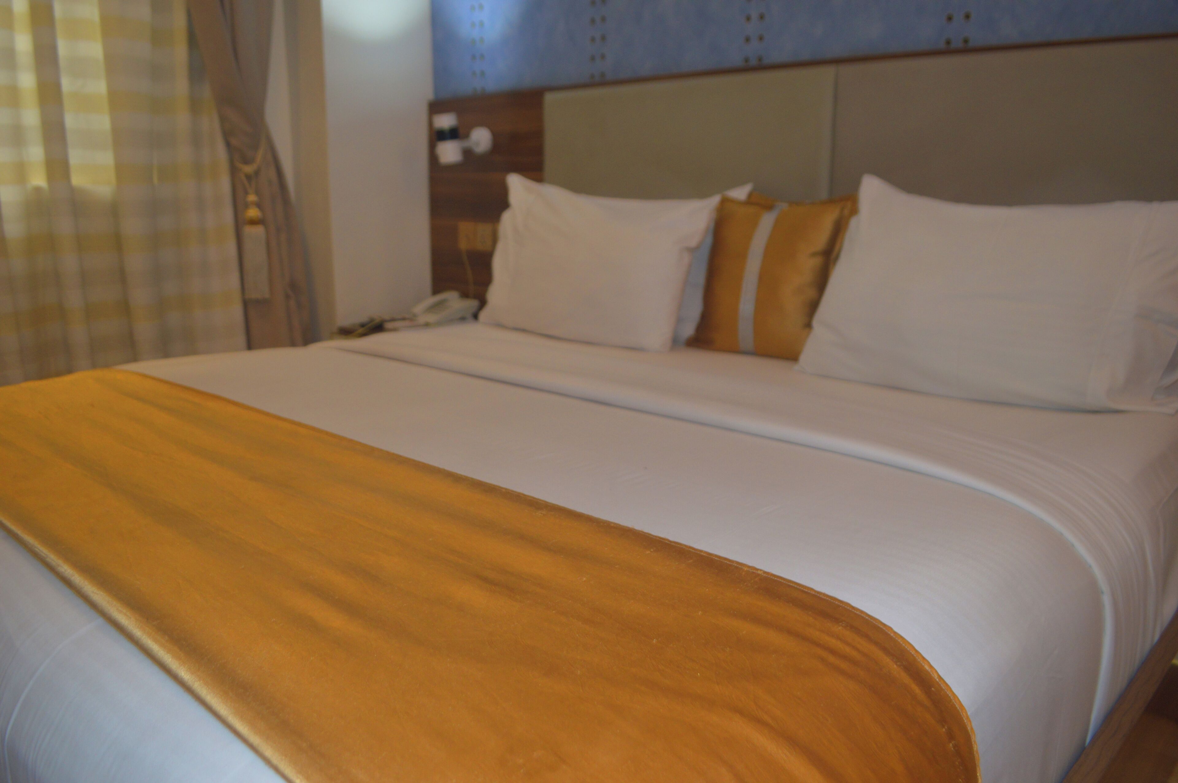 Een hotelkamer met een groot bed, een houten hoofdeinde en een telefoon op het nachtkastje.