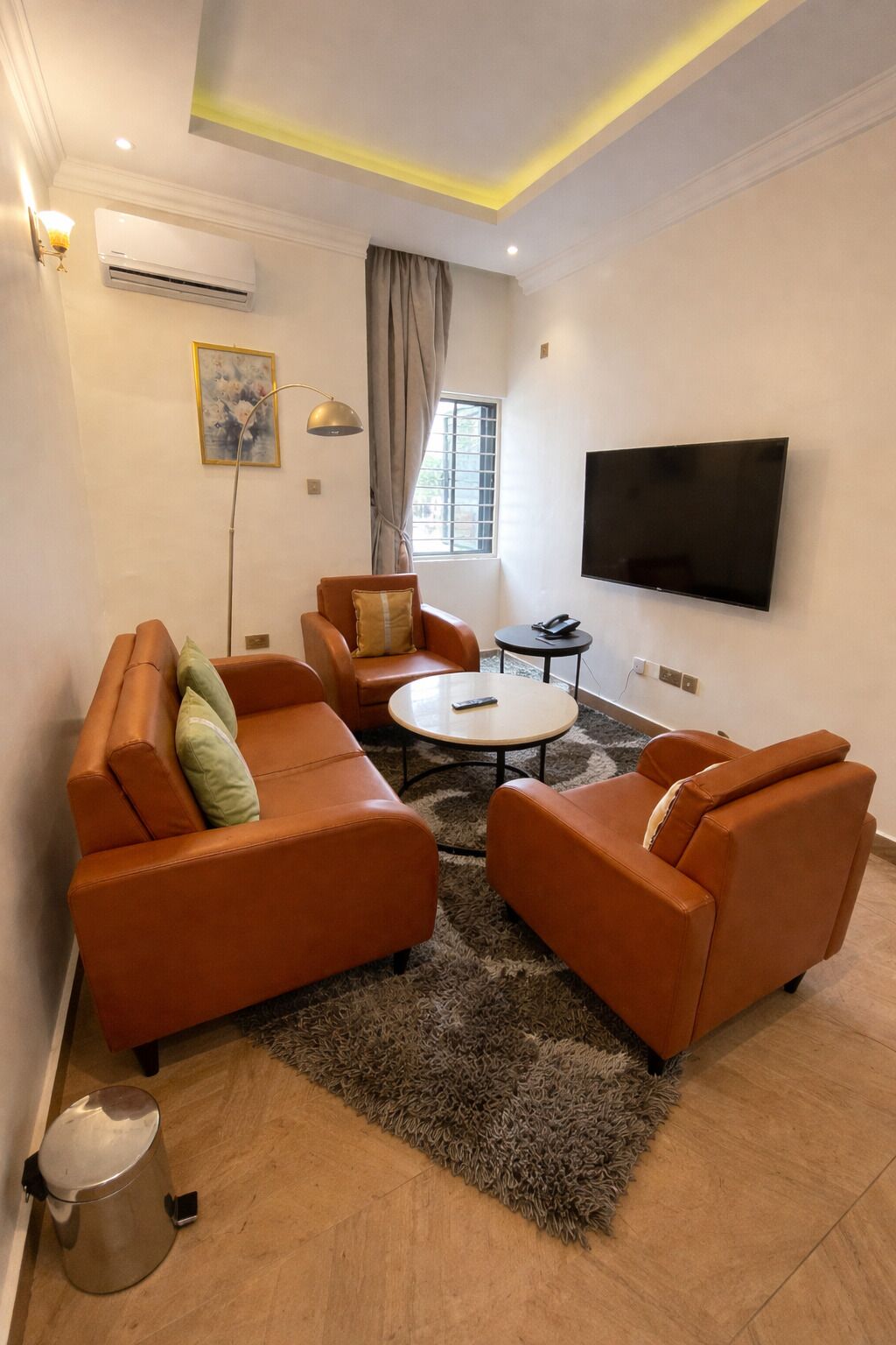 Un salon comprenant un canapé, une table basse, un téléviseur et une fenêtre avec des rideaux.