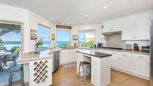 Una cocina con armarios blancos, una estufa de acero inoxidable y vistas al océano.
