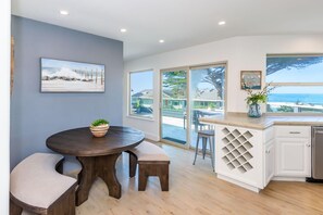A modern kitchen with a large island, white cabinetry, and a view of the ocean. - Oceanfront Home Retreat w/ Breathtaking Views of Fitzgerald Marine Reserve (Moss Beach)
