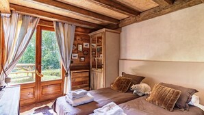 A cozy bedroom with two beds, wooden headboard, and a large window with curtains.