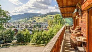 A wooden balcony with a view of a town and mountains.