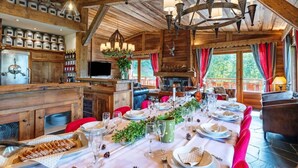 A wooden interior with a dining area set for a meal, a television, and a fireplace.