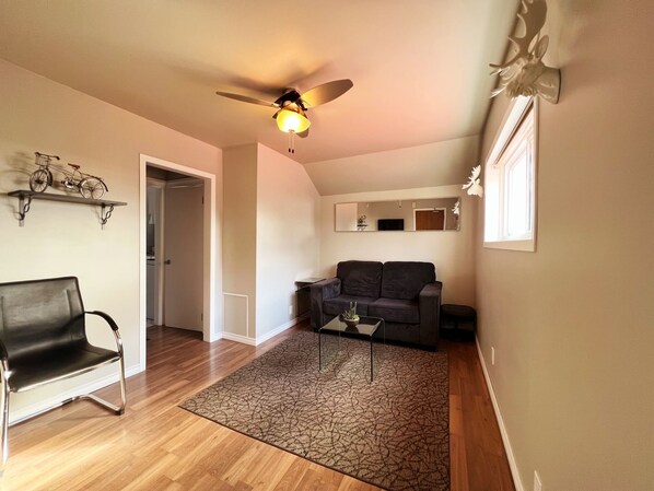 A living room with a ceiling fan, a sofa, a coffee table, and a patterned rug.