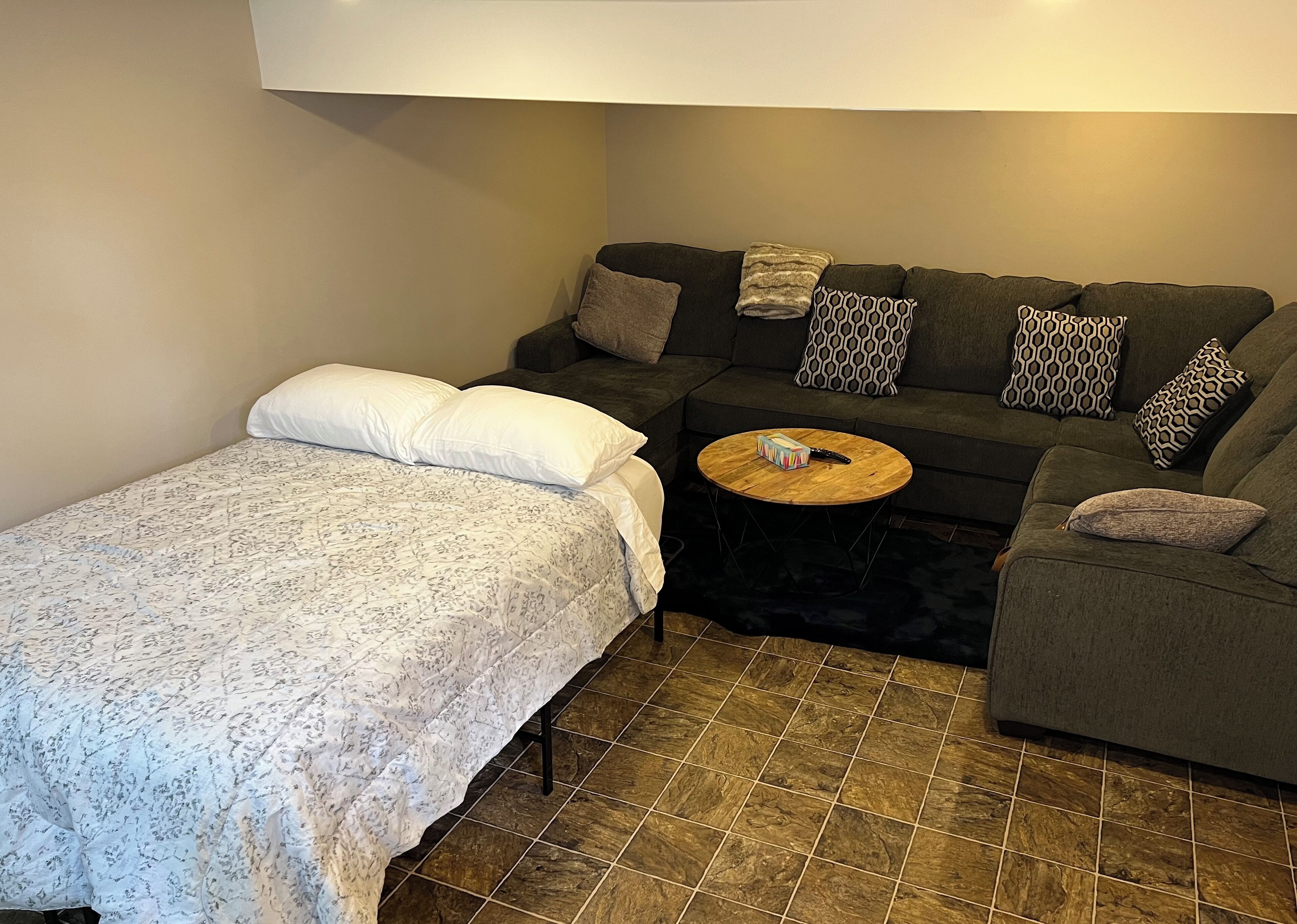 A small, cozy room with a bed, a sofa, and a coffee table.