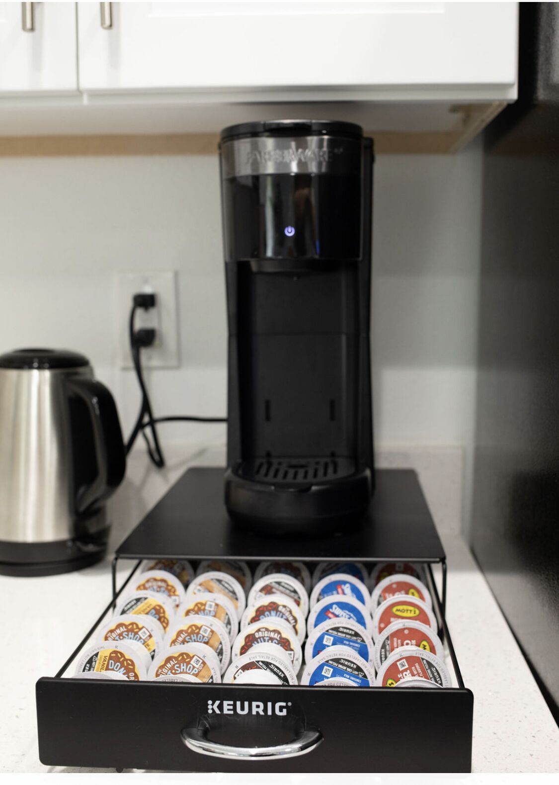 Máquina de café Keurig em uma bancada, com um suporte para cápsulas de café abaixo.