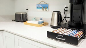 Pieni keittiönurkkaus, jossa on kahvinkeitin, leivänpaahdin ja laatikko Keurig-kahvikapseleita.