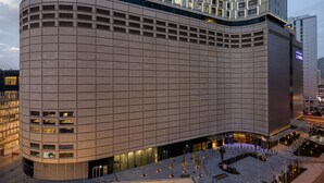 Ein modernes Hotel mit geschwungener Fassade, mehreren Etagen und einem großzügigen Eingangsbereich mit Außenplätzen.