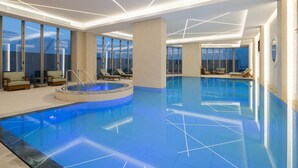 Ein modernes Hallenbad mit Whirlpool, Liegestühlen und großen Fenstern mit Blick.
