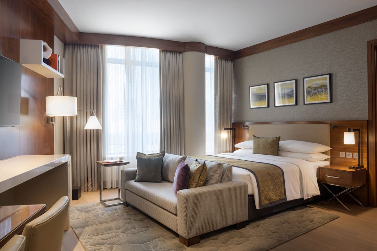 Ein Hotelzimmer mit Bett, Sofa, Schreibtisch und Lampe.