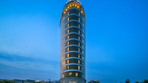 A tall, modern hotel with a curved facade and illuminated windows. - Four Points By Sheraton Ikot Ekpene (Ikot Ekpene)