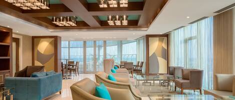 A spacious lobby with modern furniture, large windows, and a high ceiling with unique lighting fixtures.