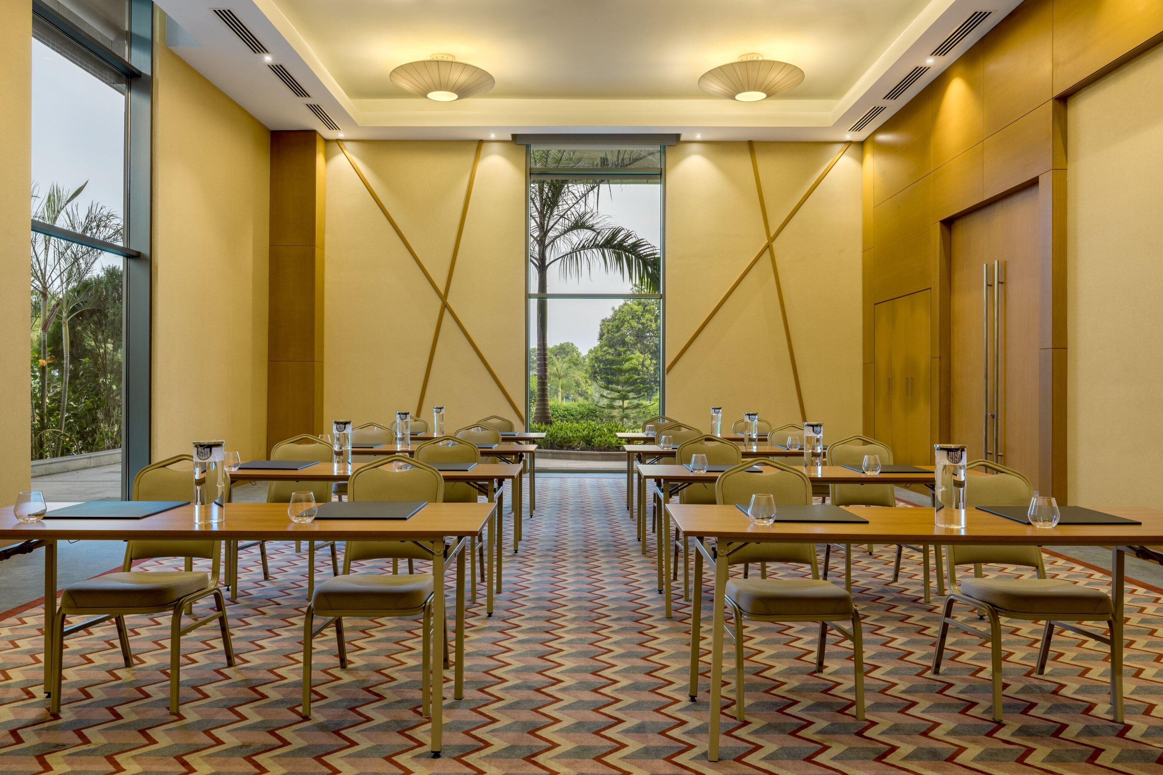 A conference room with tables and chairs, large windows, and a patterned carpet.
