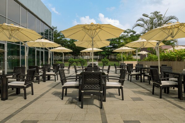 An outdoor patio with multiple tables and chairs, each with a large umbrella.