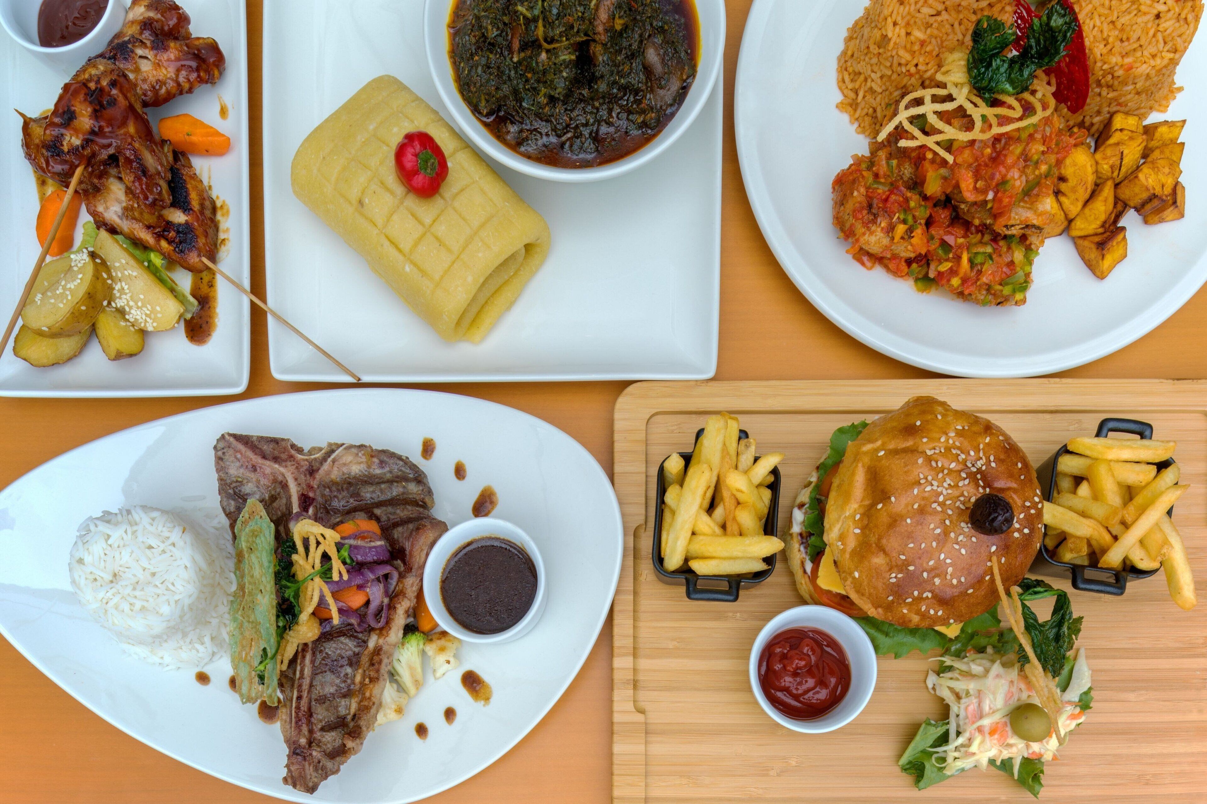 A variety of dishes including grilled meat, rice, and a burger with fries.