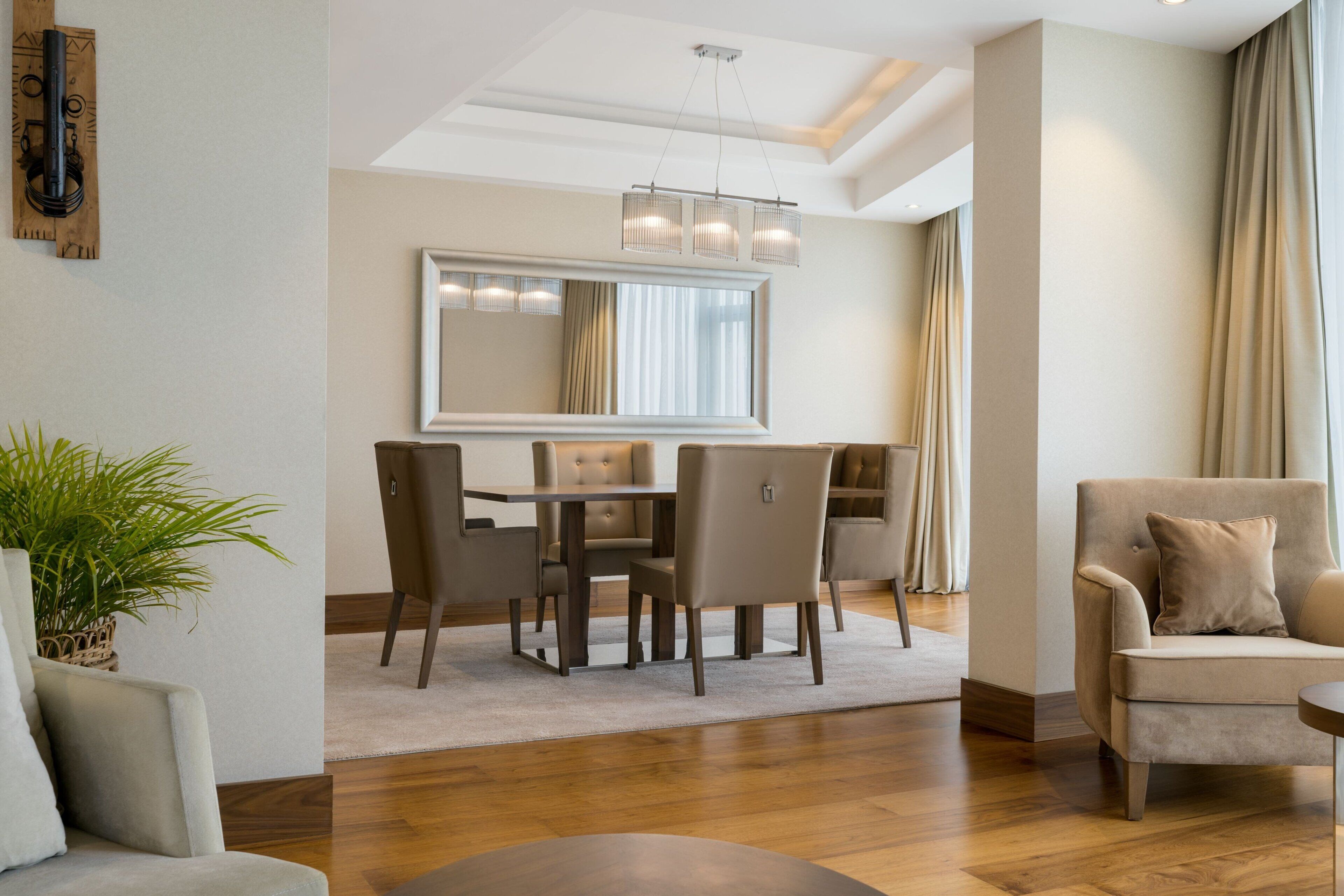 Una sala moderna con comedor, sofá, mesa de centro y un espejo grande.