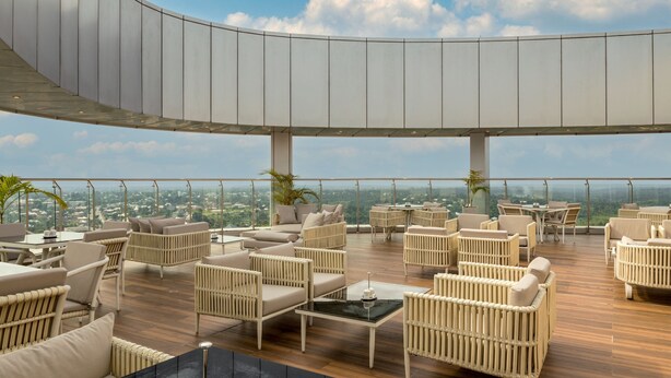 A rooftop lounge with wicker furniture, a curved ceiling, and a panoramic view of the city. - Four Points By Sheraton Ikot Ekpene (Ikot Ekpene)