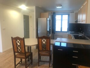 A compact kitchen with a dining table and chairs, a refrigerator, a stove, and a window with curtains. - House ✅ Near Chartres ❤️ 5 Beds 🅿️ (Corancez)