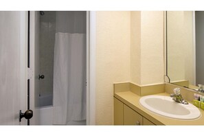 Een bad/douchecombinatie, een haardroger, handdoeken, zeep