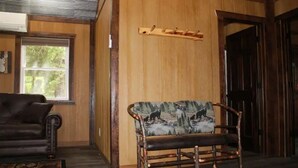 Un interior de madera con un sofá, un banco y un perchero.