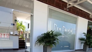 Exterior del Hotel Don David, con una entrada despejada, una recepción y plantas en macetas.