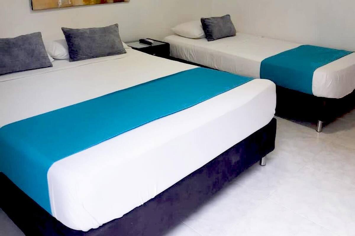 A hotel room with two beds, a painting on the wall, and a white floor.
