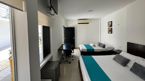 Una habitación de hotel con cama, escritorio, silla, televisor y ventana.