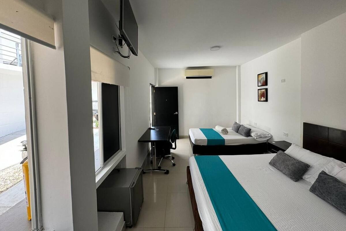 A hotel room with a bed, a desk, a chair, a TV, and a window.