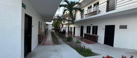 A corridor with a central walkway flanked by buildings, some with balconies and windows.