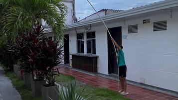 Una persona sostiene una bandera frente a un edificio con un paseo adoquinado y plantas en macetas.