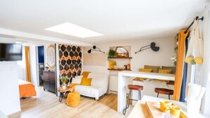 Una sala de estar moderna con sofá, mesa de centro y zona de comedor con taburetes.